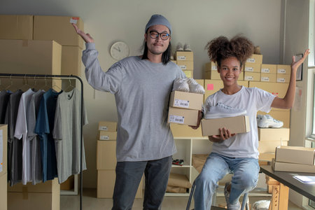 Confident mixed race young couple of Asian man and african-american woman retail seller, entrepreneur, online store drop shipping small business owner looking at camera in delivery shipping warehouseの写真素材