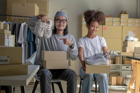 Confident mixed race young couple of Asian man and African-American woman retail seller, entrepreneur, online store drop shipping small business owner looking at camera in delivery shipping warehouseの写真素材