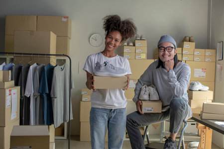 Confident mixed race young couple of Asian man and african-american woman retail seller, entrepreneur, online store drop shipping small business owner looking at camera in delivery shipping warehouseの写真素材