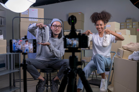 Mixed race couple of Asian man and African-American woman blogger or vlogger looking at camera reviewing product.の写真素材