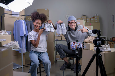 Mixed race couple of Asian man and African-American woman blogger or vlogger looking at camera reviewing product.の写真素材