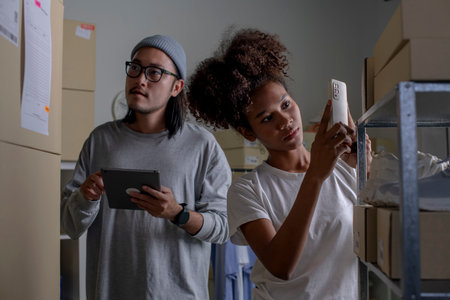 Mixed race couple of Asian man and African-American woman online seller checking stock and Inventory before sending to the customer.の写真素材