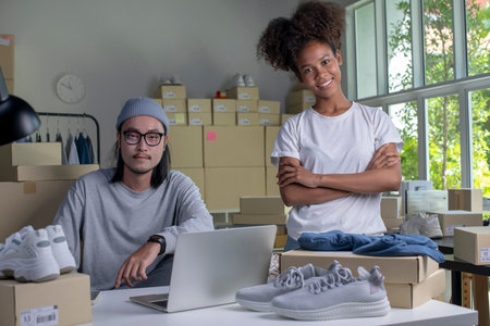 Confident mixed race young couple of Asian man and african-american woman retail seller, entrepreneur, online store drop shipping small business owner looking at camera in delivery shipping warehouseの写真素材