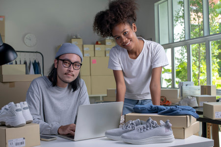 Confident mixed race young couple of Asian man and African-American woman retail seller, entrepreneur, online store drop shipping small business owner looking at camera in delivery shipping warehouseの写真素材