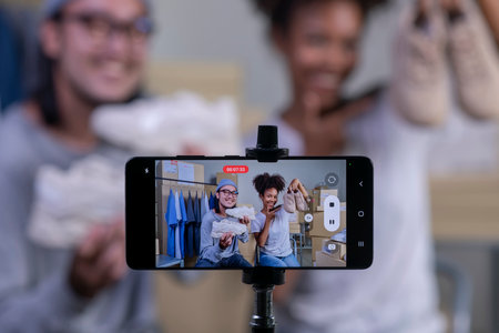 Mixed race couple of Asian man and African-American woman blogger or vlogger looking at camera reviewing product.の写真素材