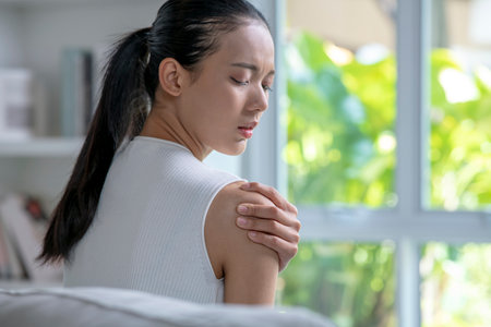 Asian woman has shoulder pain. Female holding painful shoulder with another hand. People with body-muscles problem, Healthcare And Medicine.の写真素材