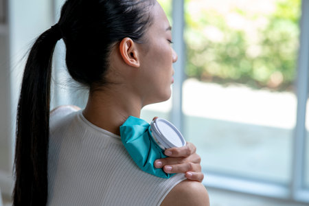 Asian woman putting a hot water bag on her shoulder pain.の写真素材