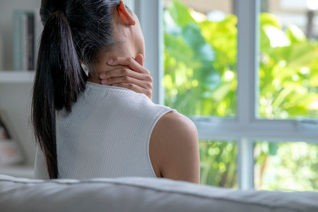 Asian woman has neck and shoulder pain. Female holding painful neck with another hand. People with body-muscles problem, Healthcare And Medicine.の写真素材