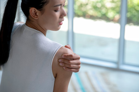 Asian woman has shoulder pain. Female holding painful shoulder with another hand. People with body-muscles problem, Healthcare And Medicine.の写真素材