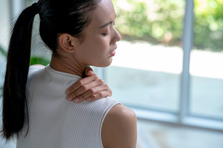 Asian woman has neck and shoulder pain. Female holding painful neck with another hand. People with body-muscles problem, Healthcare And Medicine.の写真素材