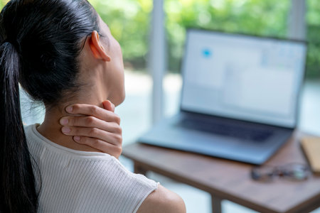 Young Asian woman suffering from neck pain in home officeの写真素材