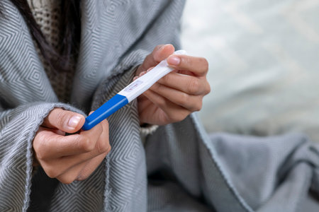 Young woman with pregnancy test in bedroom, closeupの写真素材