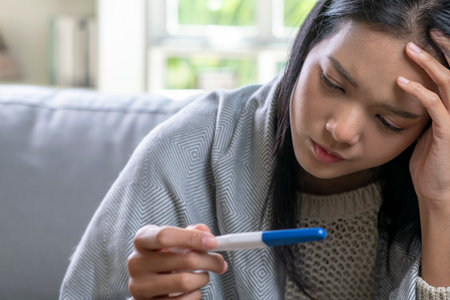 Depressed young Asian woman holding negative or positive pregnancy test.の写真素材