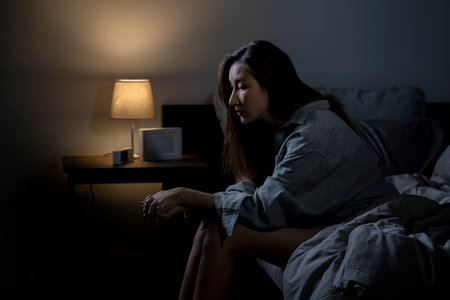 Young Asian woman in bedroom feeling sad tired and worried suffering depression in mental health, woman sitting in bed cannot sleep from insomnia.の写真素材