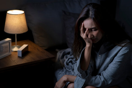 Young Asian woman in bedroom feeling sad tired and worried suffering depression in mental health, woman sitting in bed cannot sleep from insomnia.の写真素材