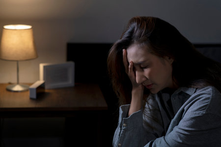 Young Asian woman in bedroom feeling sad tired and worried suffering depression in mental health, woman sitting in bed cannot sleep from insomnia.の写真素材