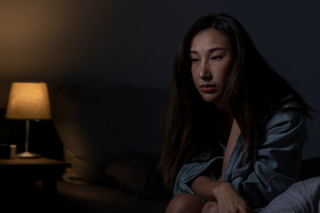 Young Asian woman in bedroom feeling sad tired and worried suffering depression in mental health, woman sitting in bed cannot sleep from insomnia.の写真素材