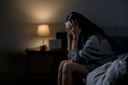 Young Asian woman in bedroom feeling sad tired and worried suffering depression in mental health, woman sitting in bed cannot sleep from insomnia.の写真素材