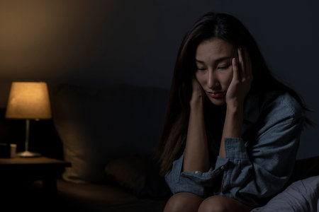 Young Asian woman in bedroom feeling sad tired and worried suffering depression in mental health, woman sitting in bed cannot sleep from insomnia.の素材