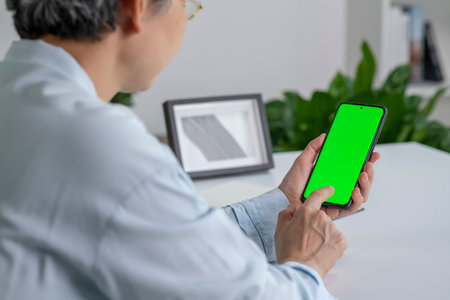 Video call. Asian woman using smartphone with blank green screen at homeの写真素材