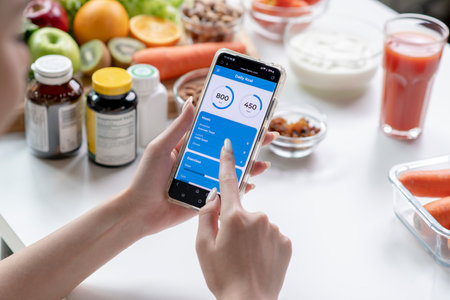 Woman professional nutritionist working and checking data from a smartphone with a variety of fruits, nuts, vegetables, and dietary supplements on the tableの写真素材