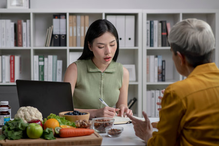 Nutritionist with woman client talking about meal plan and healthy products during a medical consultation in the officeの写真素材