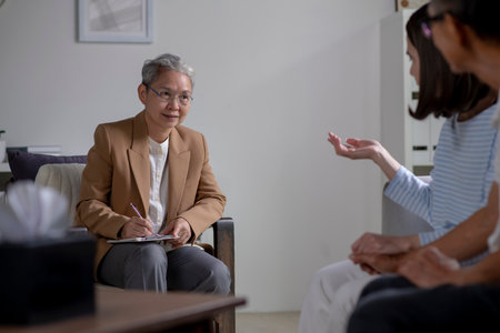Mature Asian couple consulting couple relationship counselling to solve problems. Asian psychiatrist talking to mature couple in officeの写真素材