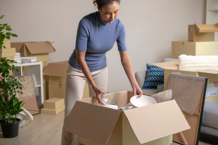 Young Asian woman moving into new house unpacking her belongings with cardboard boxes.の写真素材