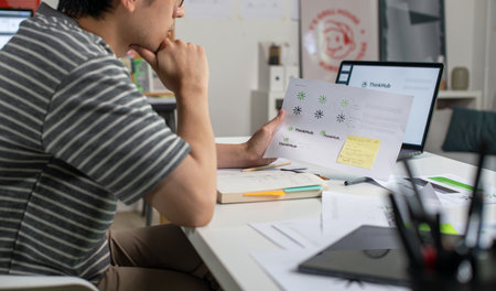 Male Asian graphic designer working in an office studio, designing logos and showcasing the corporate identity and logo design process.の写真素材