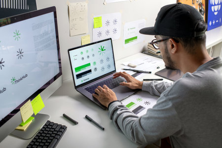 Asian graphic designer making notes on logo designs, using computers, designing logos, and showcasing the corporate identity and logo design process.の写真素材
