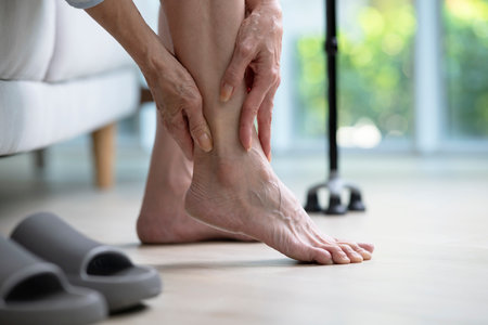 Foot pain concept, senior woman suffering from pain in ankle at home. woman rubbing, massaging sore feet area of pain, Mature woman discomfort painful feet ache from walking.の写真素材
