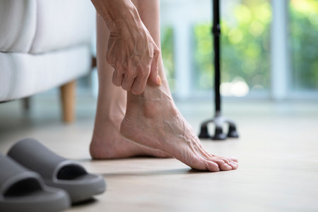 Foot pain concept, senior woman suffering from pain in ankle at home. woman rubbing, massaging sore feet area of pain, Mature woman discomfort painful feet ache from walking.の写真素材
