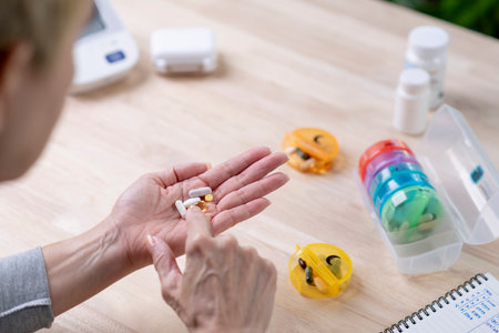 A middle-aged woman holds pills, taken from a daily pill box.の写真素材
