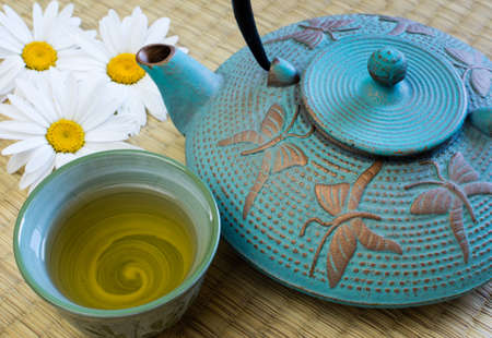 Oriental cast iron tea pot with tea cup on tatami matの写真素材
