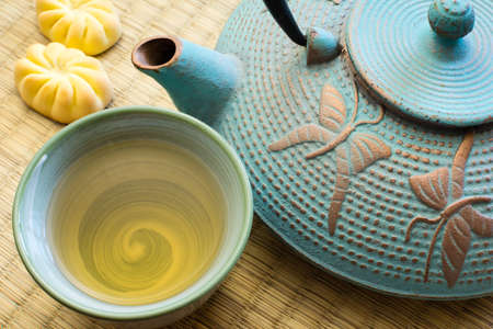 Oriental cast iron tea pot with tea cup on tatami matの写真素材