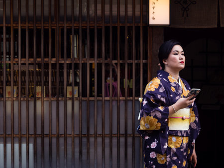 Kanazawa, Japan - September 29, 2015: Asian women in colorful kimono holding sellphone in front of traditional Japanese house in historic Higashi Chaya geisha districtのeditorial素材