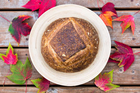 Homemade artisan bread on a round plate with fall decorationsの写真素材