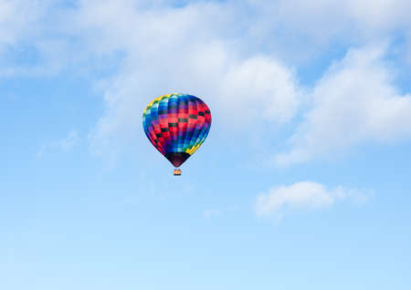 Colorful hot air balloon flying in the blue sky with soft clouds - at Winthrop Balloon Festival, Washington stateの写真素材