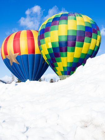 Two colorful hot air balloons on a snowy field ready to take off - at Winthrop Balloon Festival, Washington stateのeditorial素材