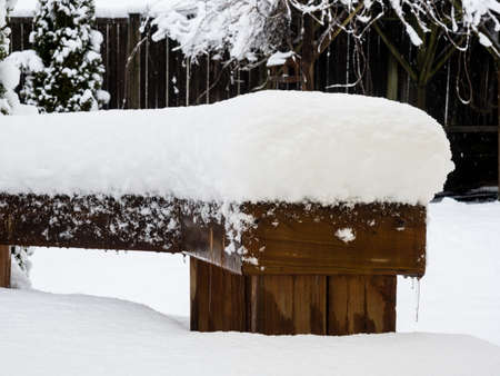 Wooden bench, deck and backyard covered in deep snow - Washington state, USAの写真素材