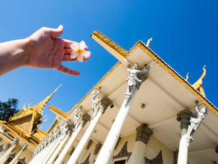 Phnom Penh, Cambodia - February 11, 2017: Tourist holding frangipani flower against the backdrop of the Throne Hall inside the Royal Palace of Cambodiaのeditorial素材