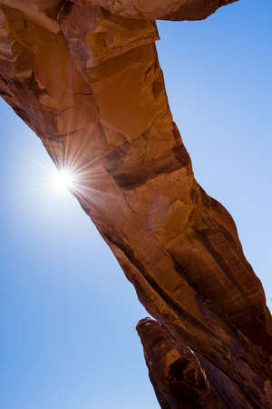 Sun peeking from behind the Pine Tree Arch in Arches National Park - Moab, Utah, USAの写真素材