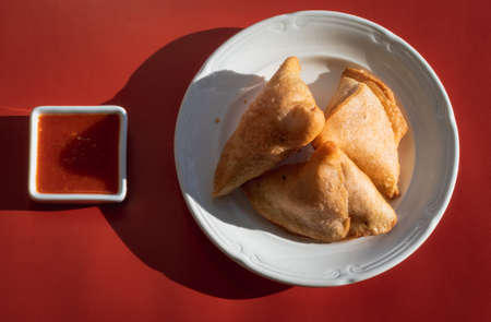 Samosas on a white plate and red sauceの写真素材