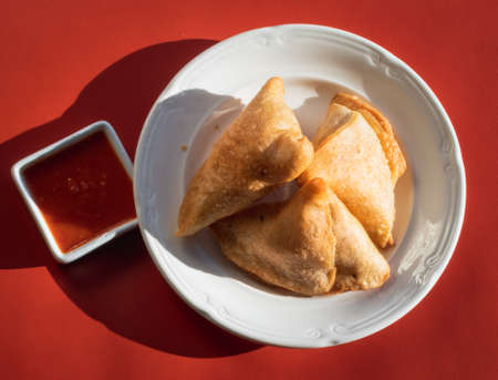 Samosas on a white plate and red sauceの写真素材