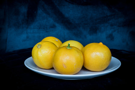 Persian Sweet lemons on a white plate with dark blue backgroundの写真素材