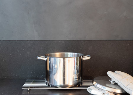Hot cooking pot and mittens on a gray dark kitchen topの写真素材