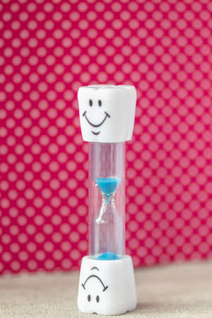 hourglass with smile and colored sand pouring