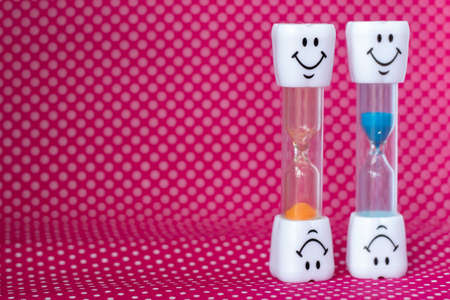 hourglass with smile and colored sand pouringの写真素材