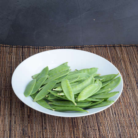 mangetout peas in a white plateの写真素材