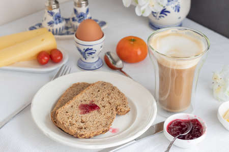 Breakfast table with bread, coffee, cheese, egg, jamの写真素材
